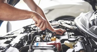 Picture showing muscular car service worker repairing vehicle.