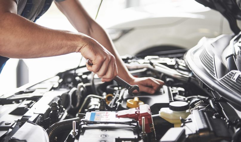 Picture showing muscular car service worker repairing vehicle.