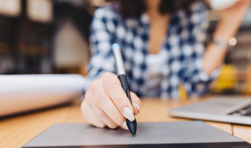 Closeup image hand of woman designing on table in library surround work stuff. Laptop, creative work, graphic design, freelancer, smart student, love job