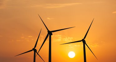 Green renewable energy concept - wind generator turbines in sky on sunset