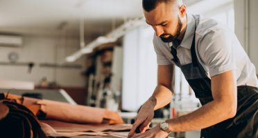 Male designer and leather tailor working at a factory