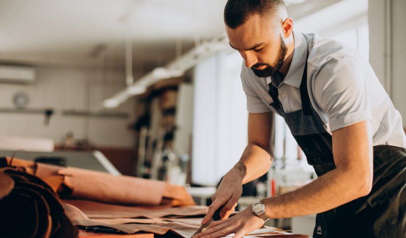 Male designer and leather tailor working at a factory