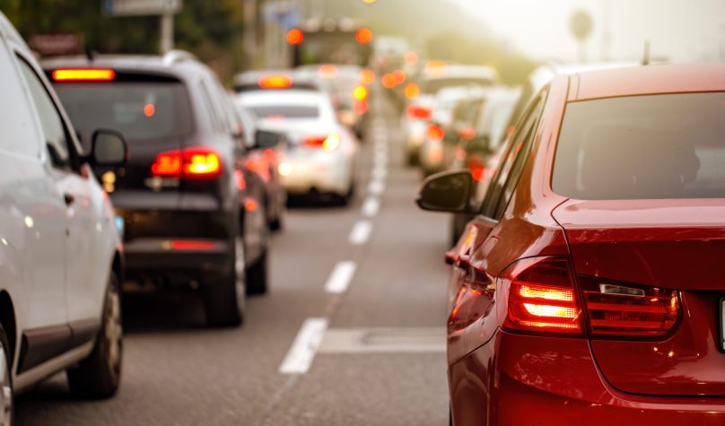 Rear view of modern car with brake lights on during rush hour. Concept of irritation of being delayed by traffic jam. Road full of vehicles in panoramic composition.
